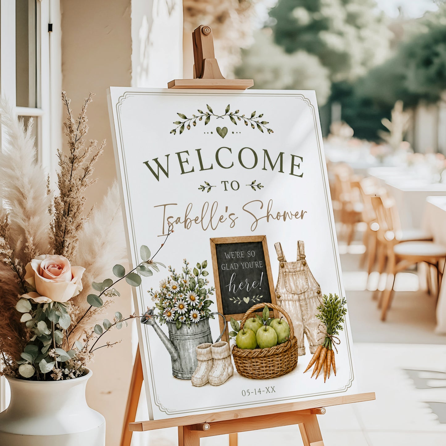 Homegrown baby shower welcome sign with a watering can, green apples, and baby overalls in sage green and neutral