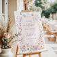 Editable wildflower baby shower welcome sign Canva template with watercolour roses, lavender, cosmos, blush arch, and butterfly details in soft pink and purple tones