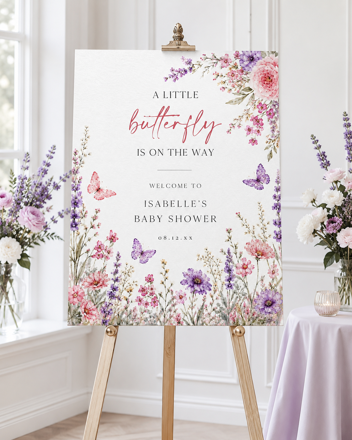Editable butterfly baby shower welcome sign Canva template with watercolour pink and purple butterflies, peonies, lavender, and wildflower meadow on a white background, shown as a hanging print mockup