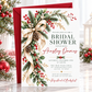 Winter bridal shower invitation with a flowing ivory bow, evergreen branches, red and white berries, snow-dusted pinecones, and gold accents on a white background