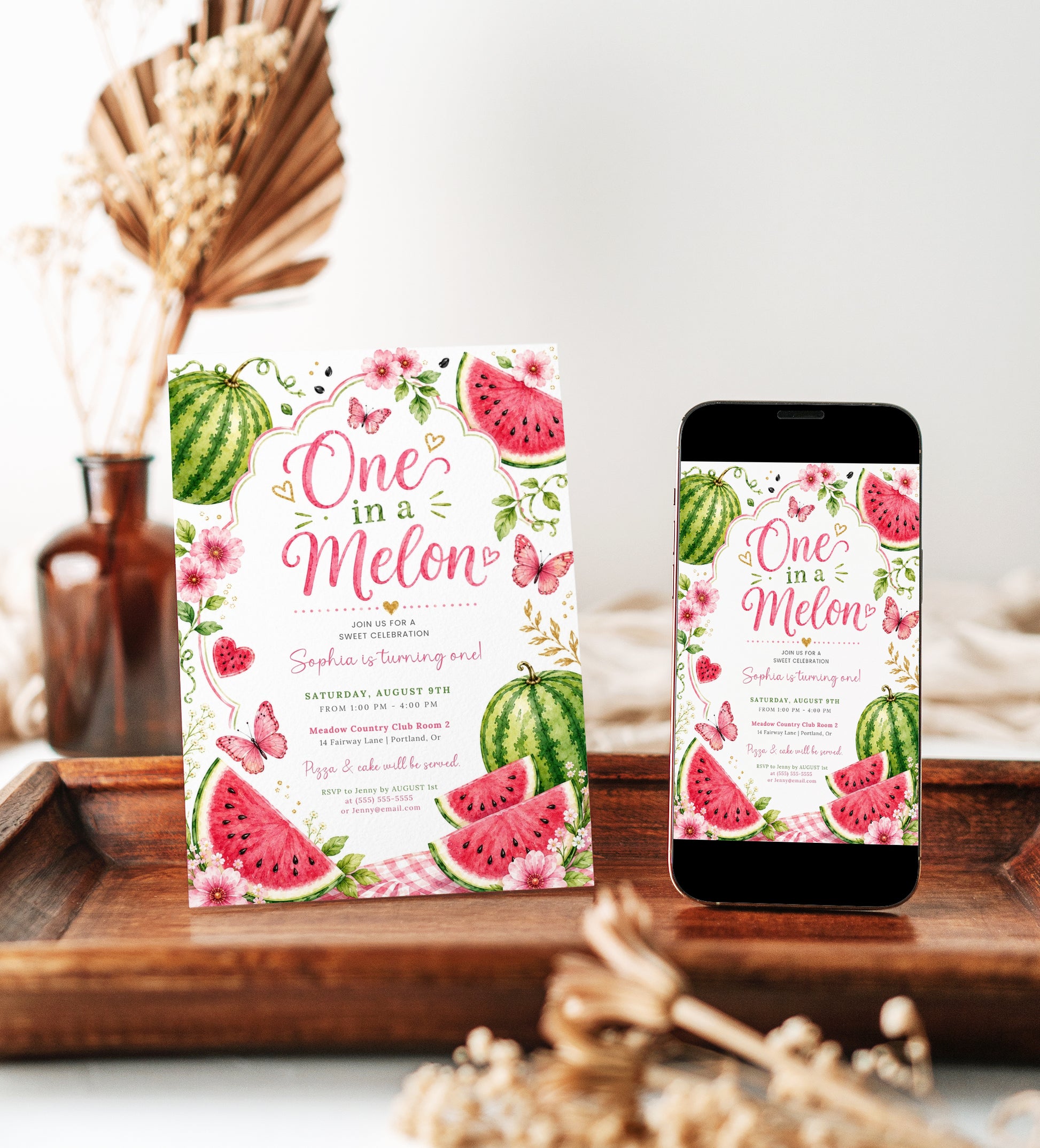 One in a Melon first birthday invitation featuring watercolor watermelons, pink flowers, butterflies, greenery and gold hearts.
