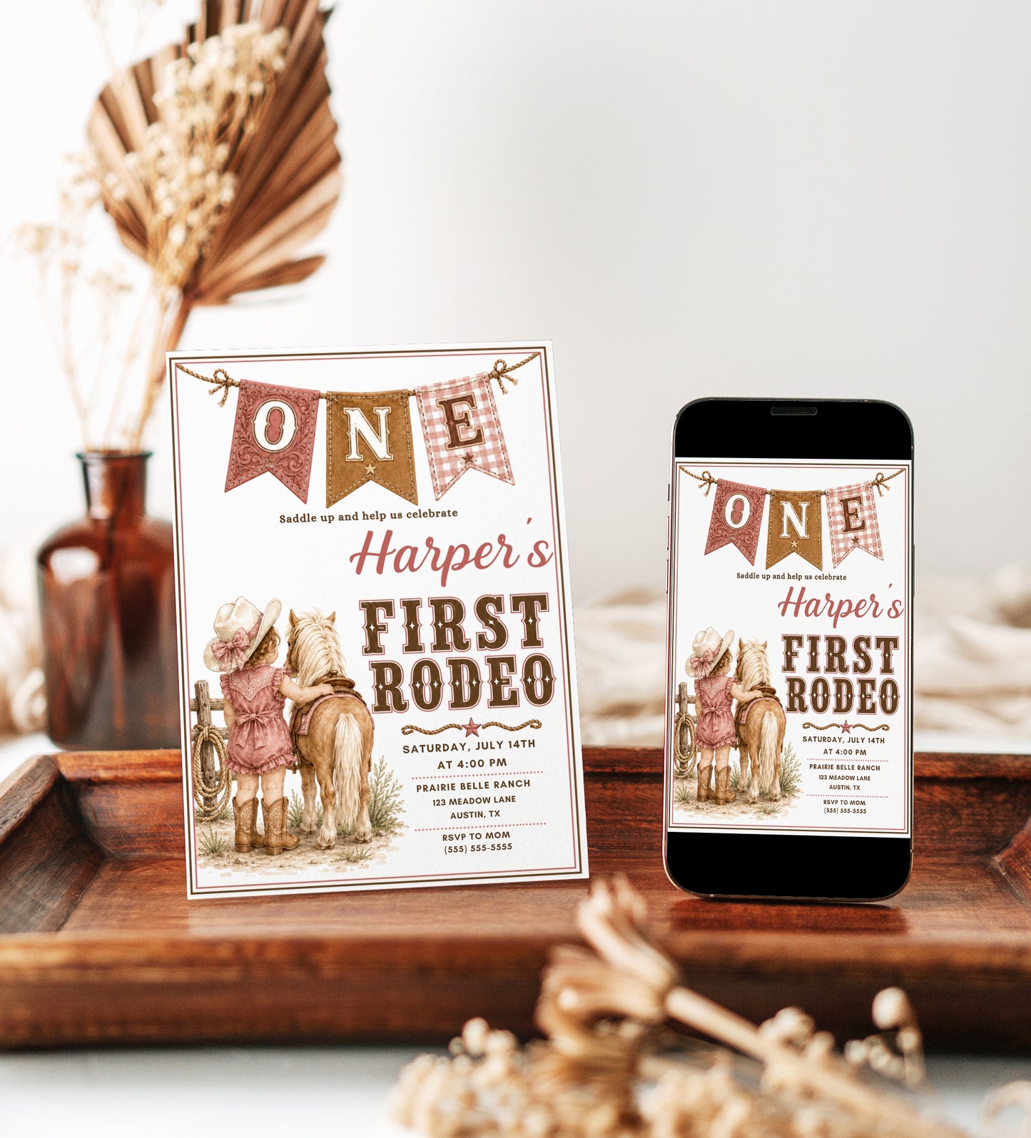 Girls 1st birthday invitation with little cowgirl, pony, cowboy hat, boots, rope details, western banner, blush pink accents, and rustic cowgirl party details
