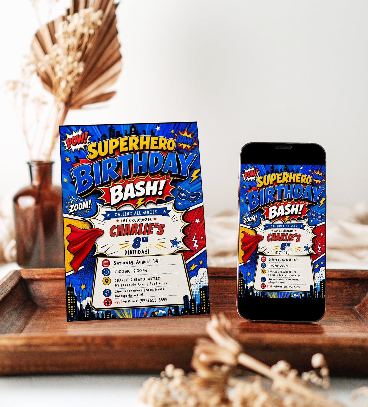 Superhero birthday invitation featuring a bold comic book design with POW, BAM and ZOOM graphics, city skyline, cape, mask, stars and lightning bolts.
