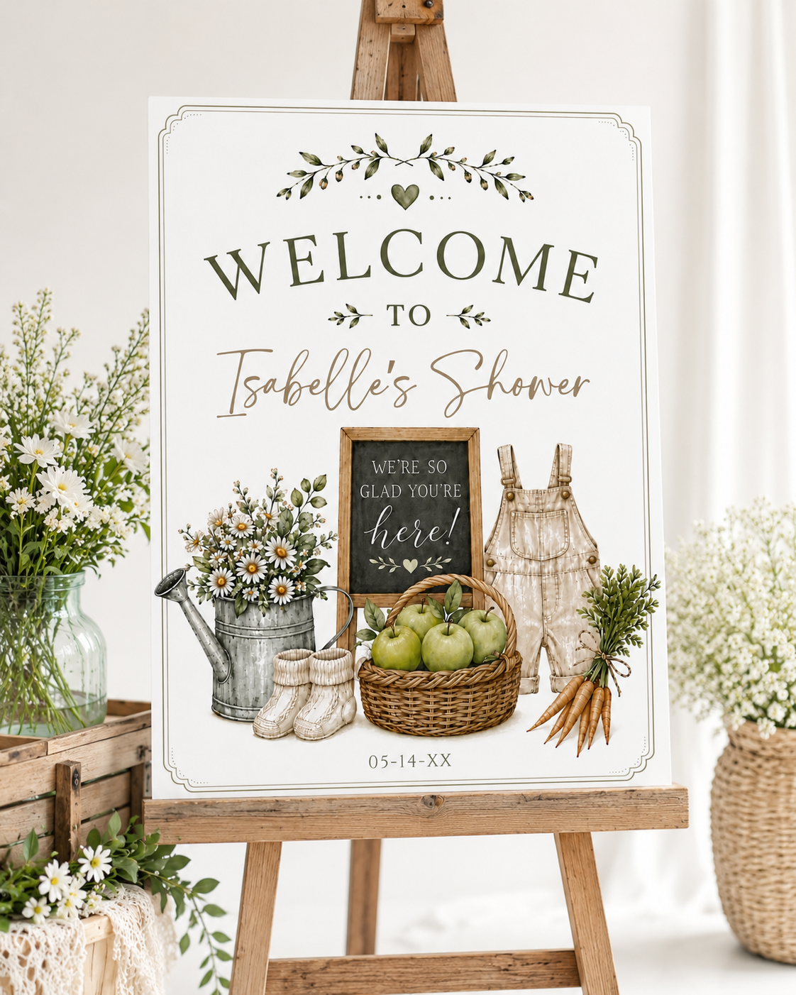 Homegrown baby shower welcome sign with a watering can, green apples, and baby overalls in sage green and neutral