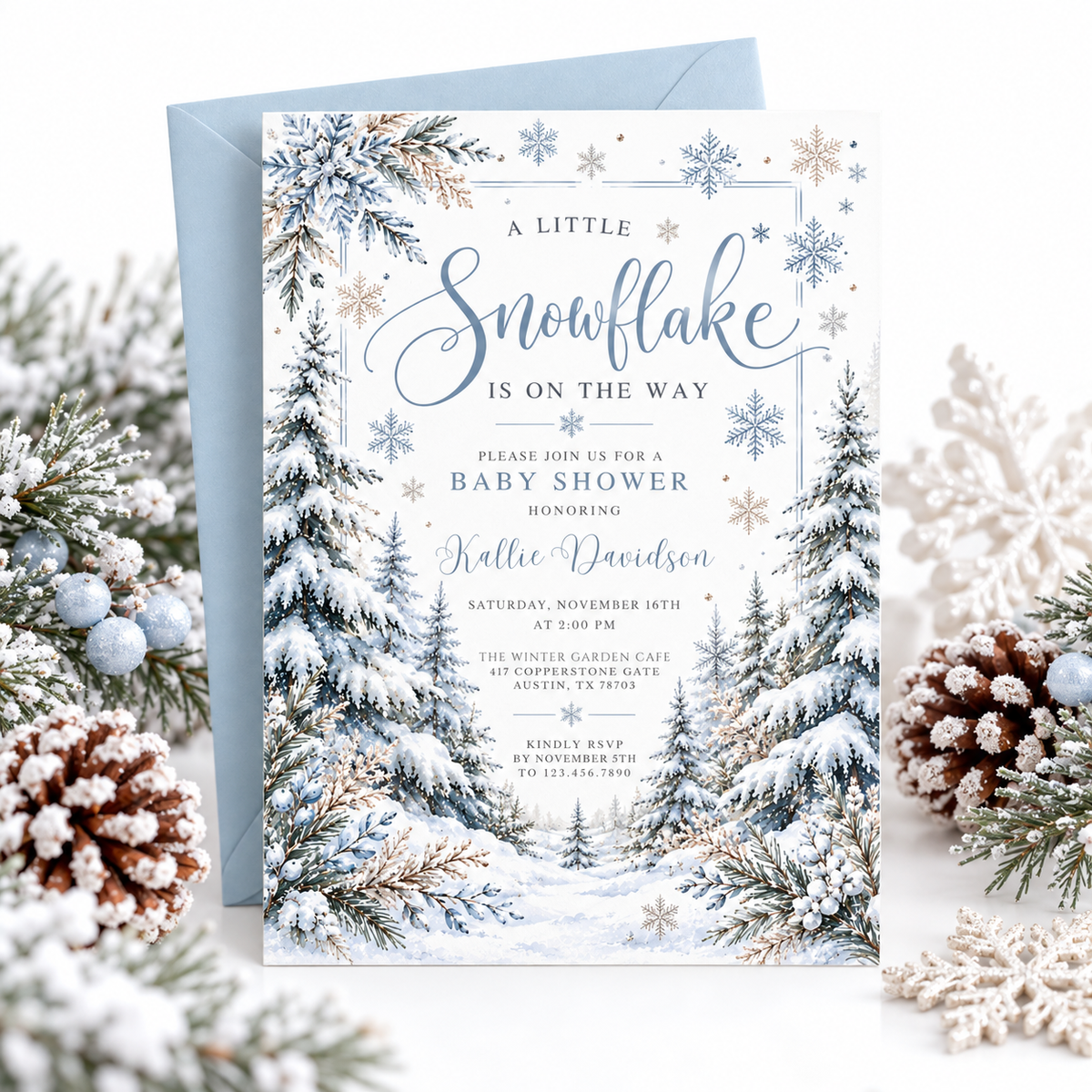 Winter baby shower invitation with blue snowflakes, snow-covered evergreen trees, frosted foliage, and A Little Snowflake Is on the Way wording on white