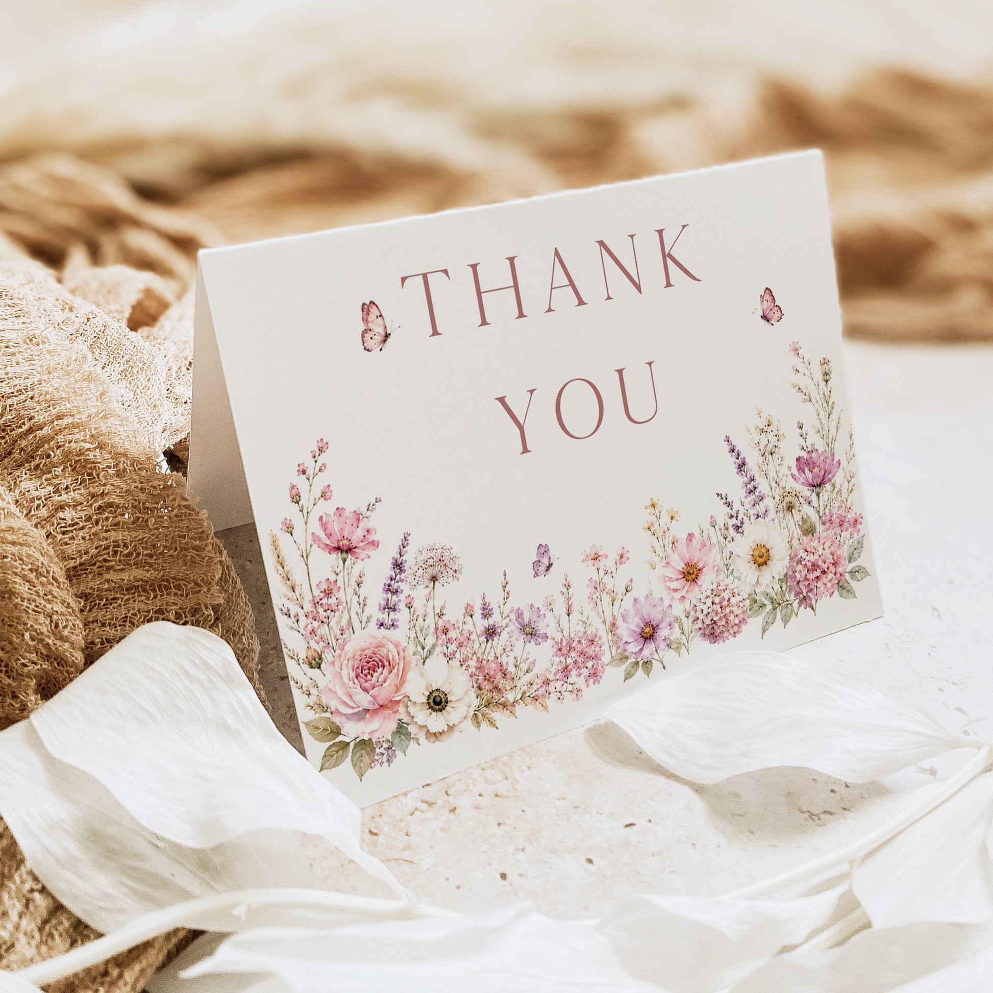 Editable wildflower folded thank you card Canva template with watercolour roses, lavender, daisies, and butterfly details on a white background, shown as a folded card mockup