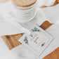 Editable blueberry baby shower gift tag Canva template with watercolour blueberry clusters, white blossoms, blue ribbon bow, and script typography on a cream arch with blue gingham background