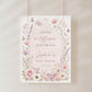 Editable wildflower baby shower welcome sign Canva template with watercolour roses, lavender, cosmos, blush arch, and butterfly details in soft pink and purple tones