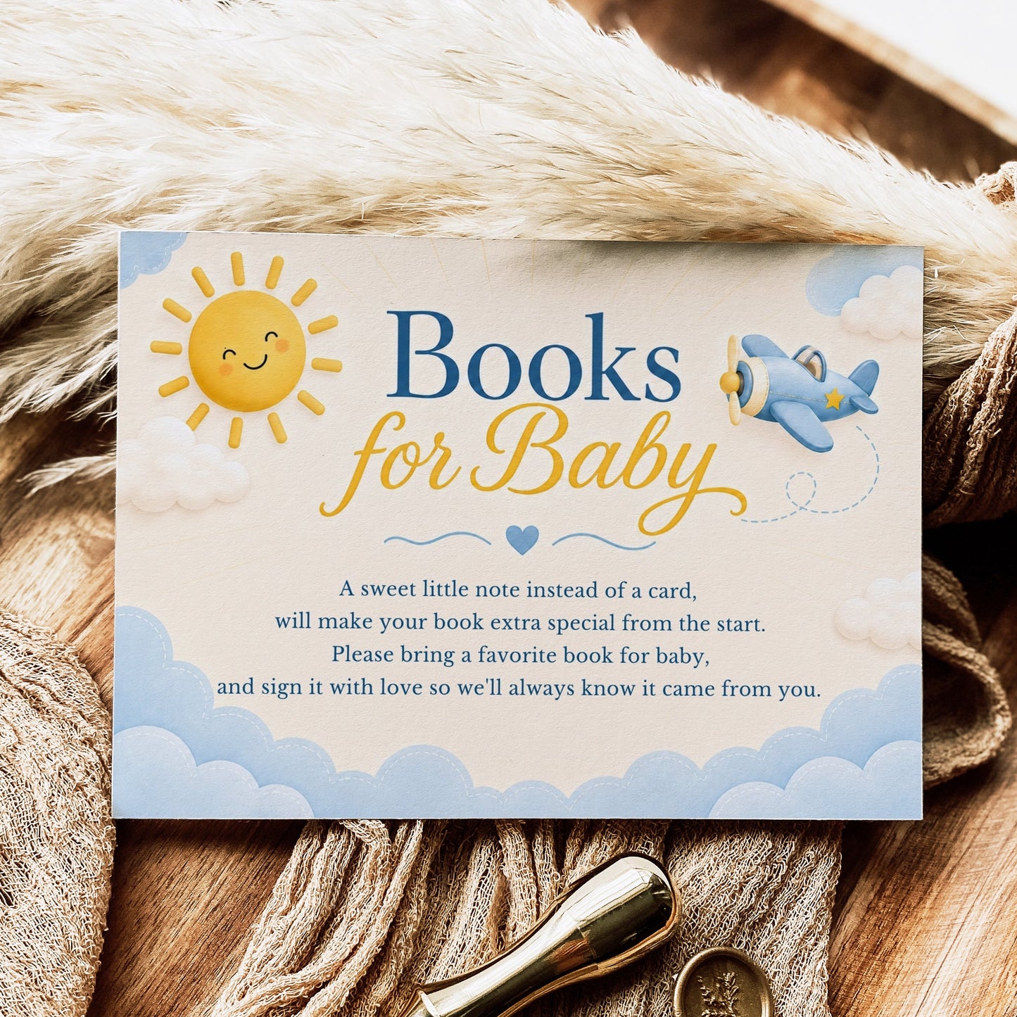 Editable here comes the son books for baby card Canva template with smiling sun, blue toy airplane, fluffy clouds, and navy and golden script typography on a warm cream background, landscape orientation
