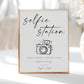 Minimalist black and white wedding selfie station sign template with calligraphy script and hand-drawn camera illustration, editable in Canva