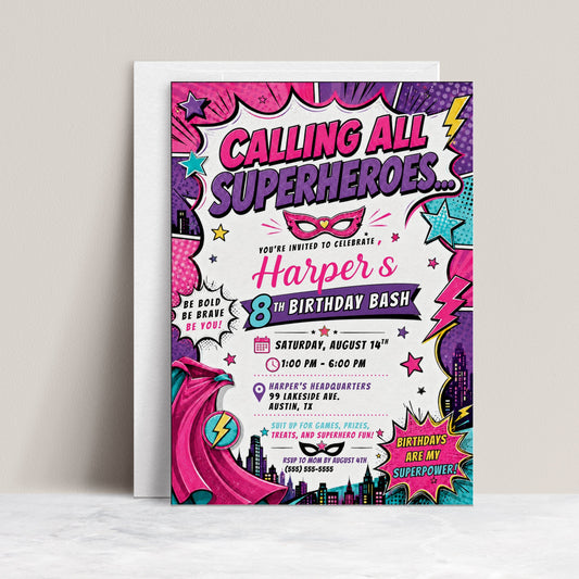 Girls superhero birthday invitation featuring a pink comic book design with cape, mask, city skyline, stars, lightning bolts and bold action graphics.
