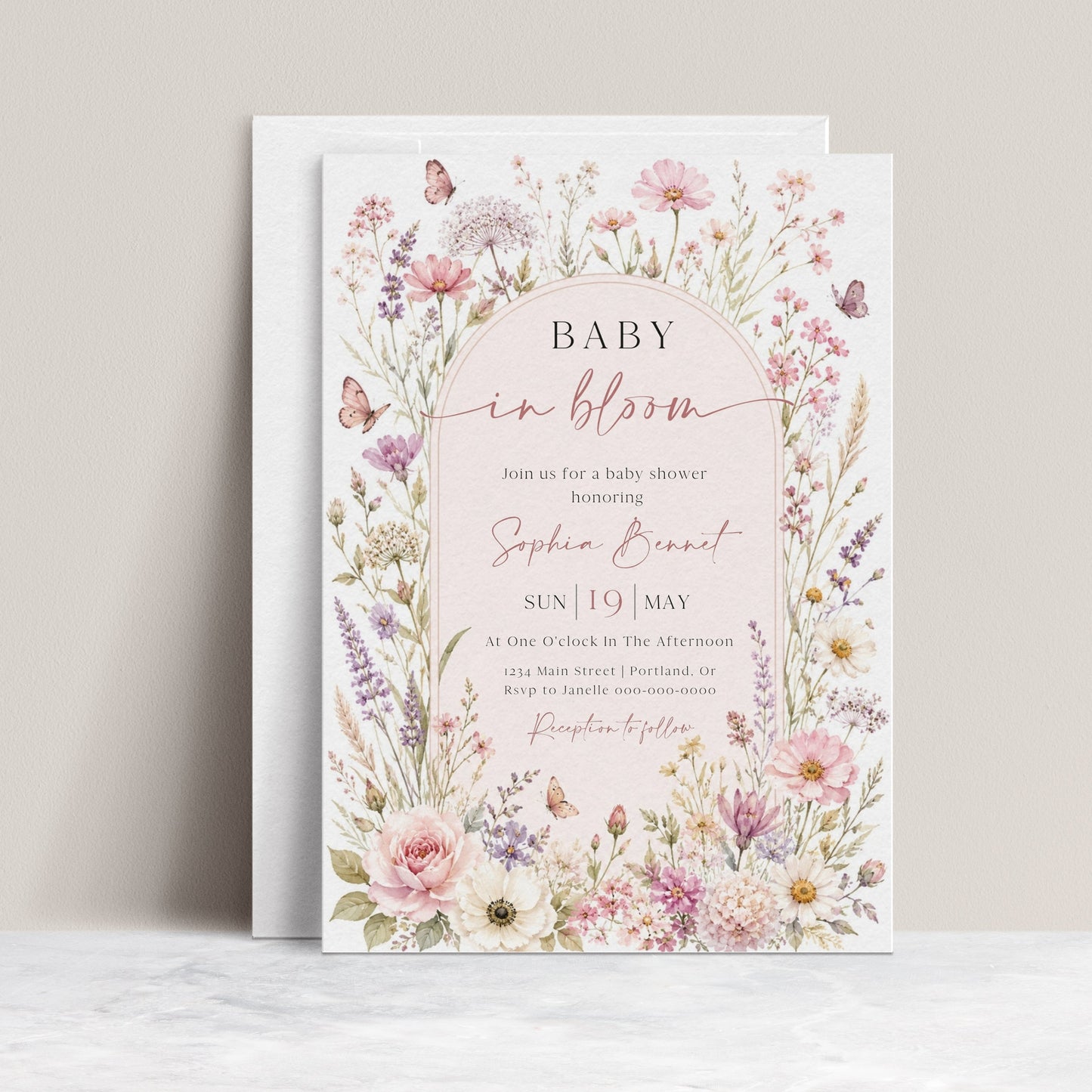 Editable baby in bloom wildflower baby shower invitation Canva template with watercolour roses, cosmos, lavender, and butterfly details framing a blush arch, shown with front and back of card