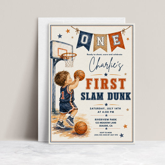 Basketball first birthday invitation featuring a little boy shooting a basketball, hoop, ONE banner, stars and navy and orange sports details.
