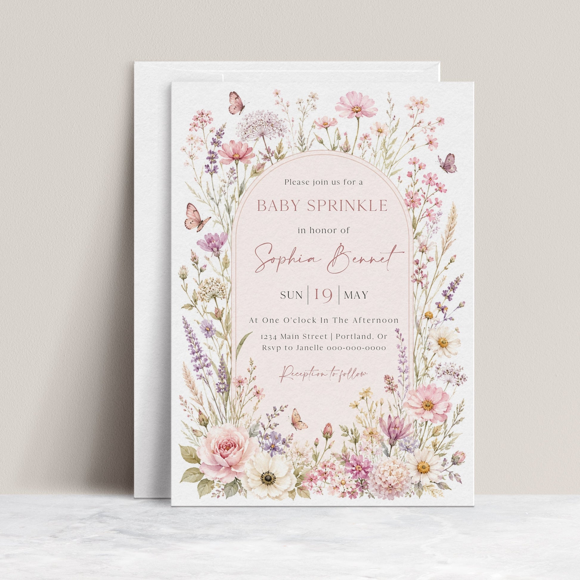 Editable wildflower baby sprinkle invitation Canva template with watercolour botanicals, blush arch, butterfly details, and script typography on a soft pink background