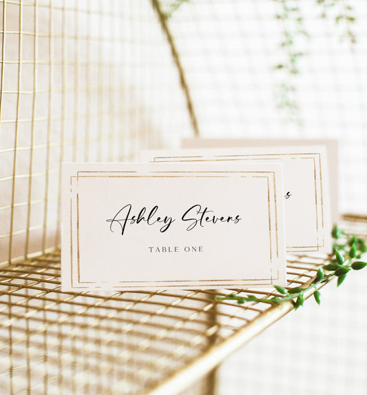 Minimalist wedding place card template with gold double frame border and elegant calligraphy script, editable in Canva